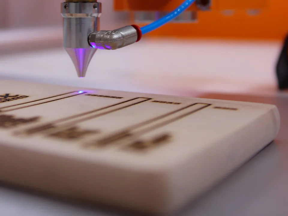Tête de gravure laser en train de graver une planche de bois