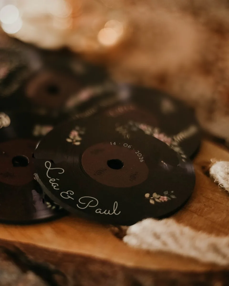 Disques façon microsillon offerts aux invités, imprimés « Léa & Paul » et 14 · 06 · 2026, sur une tranche de bois