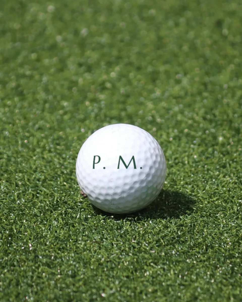 Balle de golf blanche imprimée P. M., sur un green