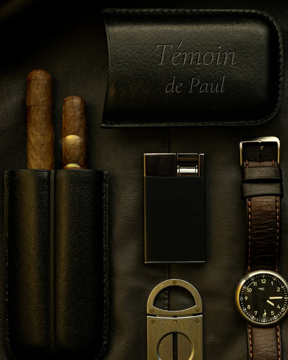 Étui de cuir noir à deux cigares, son capuchon gravé « Témoin de Paul », avec coupe-cigare, briquet et montre