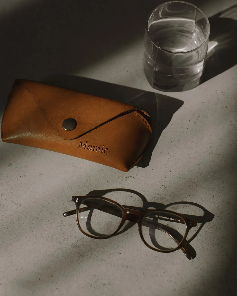 Étui à lunettes en cuir à rabat, gravé « Mamie », à côté d'une paire de lunettes