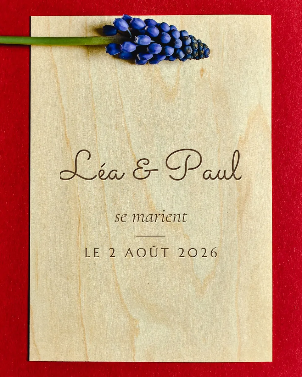 Faire-part en contreplaqué de bouleau gravé « Léa & Paul se marient, le 2 août 2026 », avec un brin de muscari