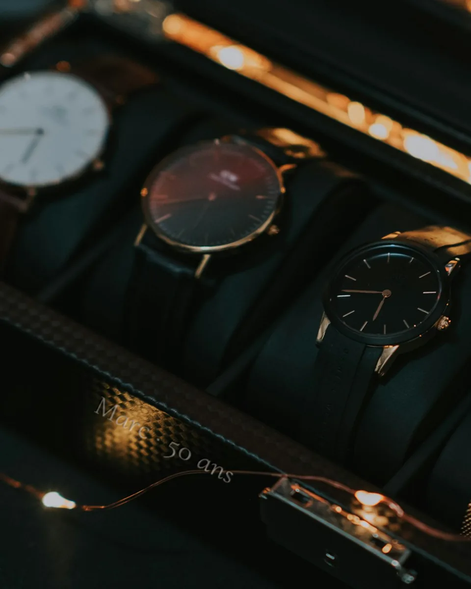 Coffret à montres ouvert, cinq montres sur coussins de cuir, façade gravée « Marc · 50 ans »