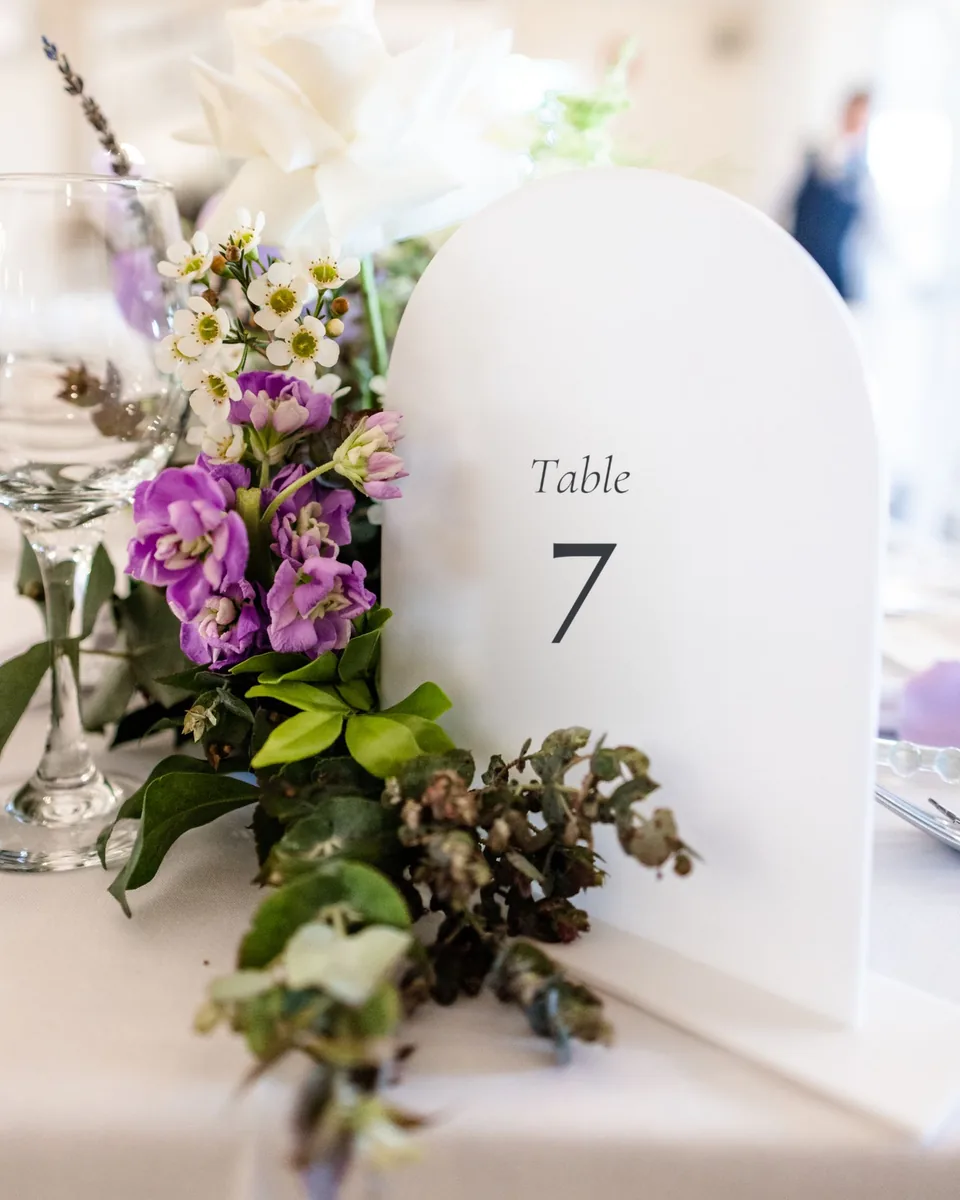 Numéro de table en arche d'acrylique blanc, Table 7, sur une table de mariage fleurie