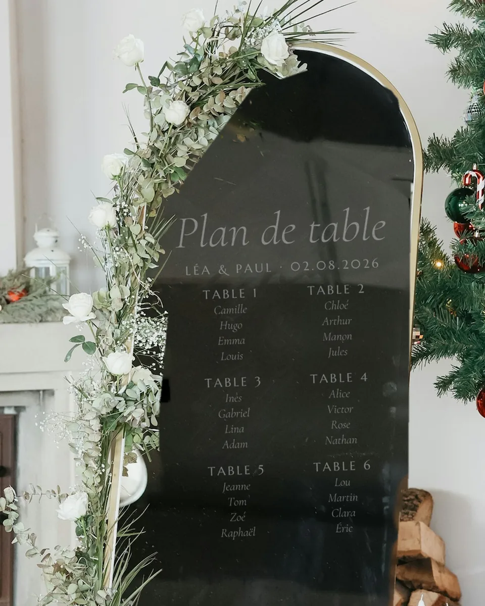 Plan de table en arche, noir cerclé de laiton, gravé de six tables et de leurs invités